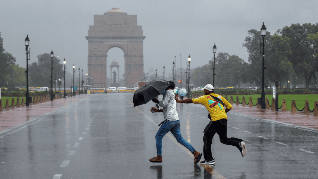 People run in heavy rain near India Gate during Delhi monsoon.