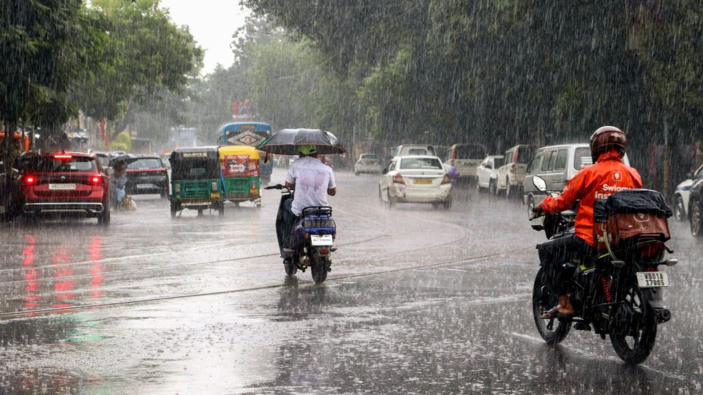 Commuters make their way through a glistening road amid heavy rain at Esplanade, Kolkata