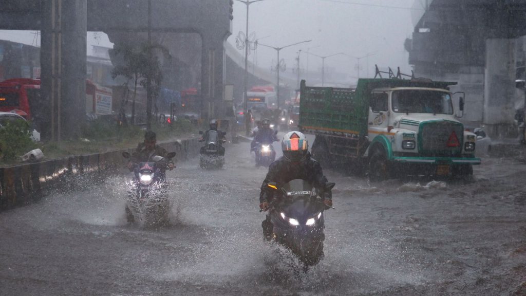 Commuters wade through a flooded road in Mumbai following heavy rainfall