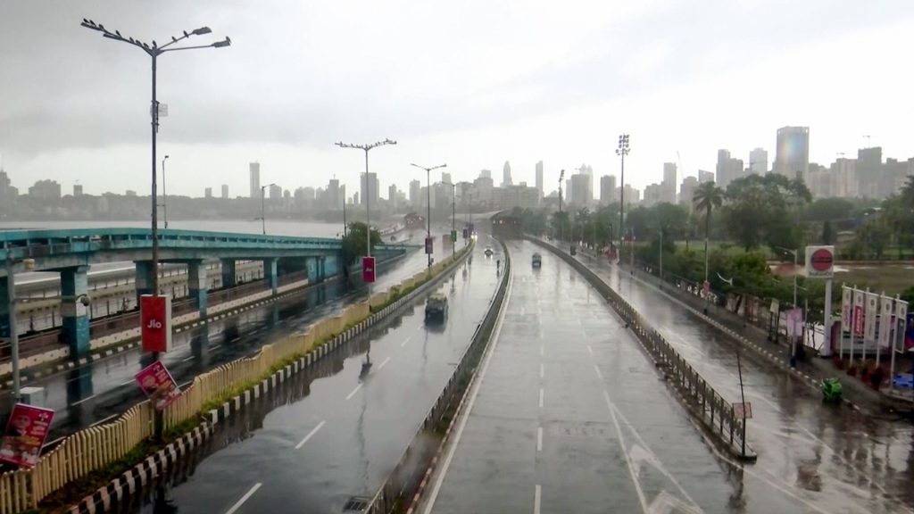 Commuters make their way through glistening roads at Marine Drive as rain lashes