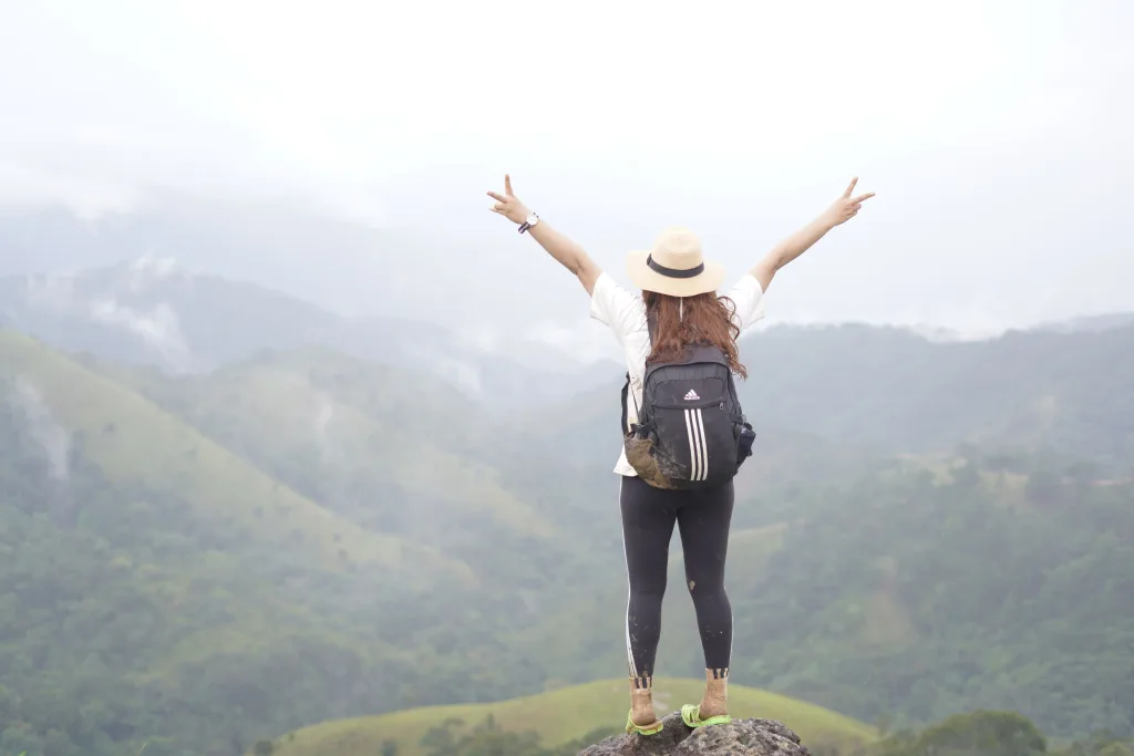 A woman hiker on a mountain top celebrating the scenic view with open arms