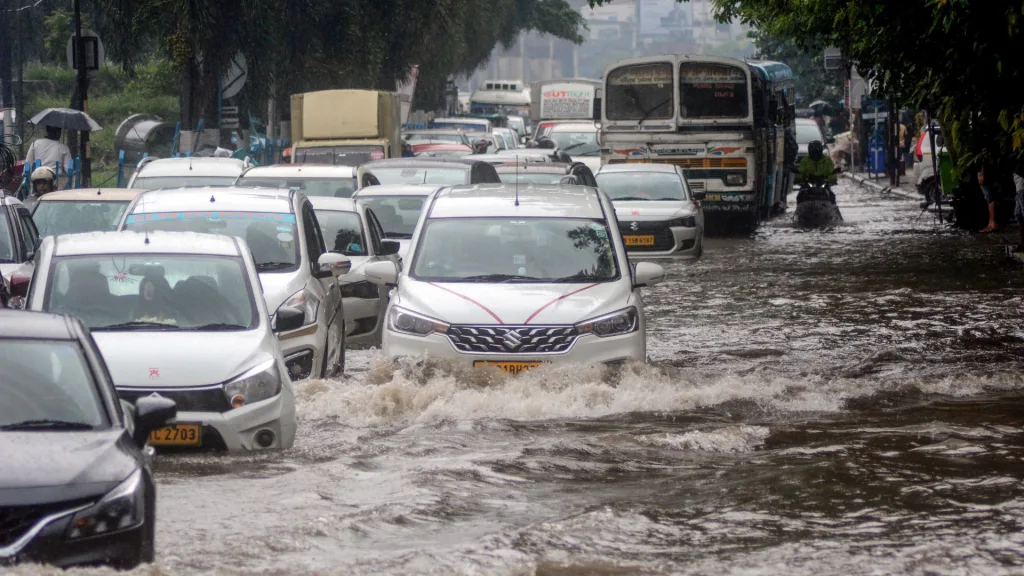 Vehicles wade through a waterlogged street after heavy rainfall