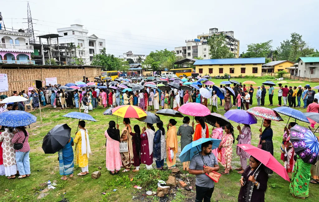 Voters queue up as they wait to cast their votes amid rain at the polling station during the Assam Assembly Elections 2026 in Guwahati on Thursday / ANI