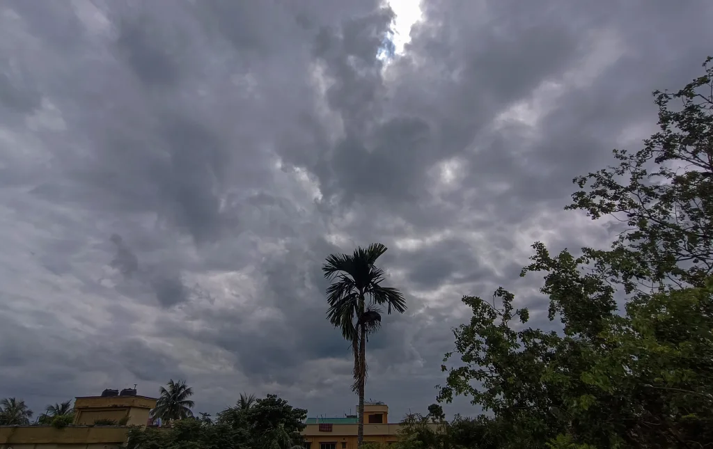 Dark monsoon clouds gather over an Indian city as IMD forecasts below-normal rainfall and above-normal temperatures for August.
